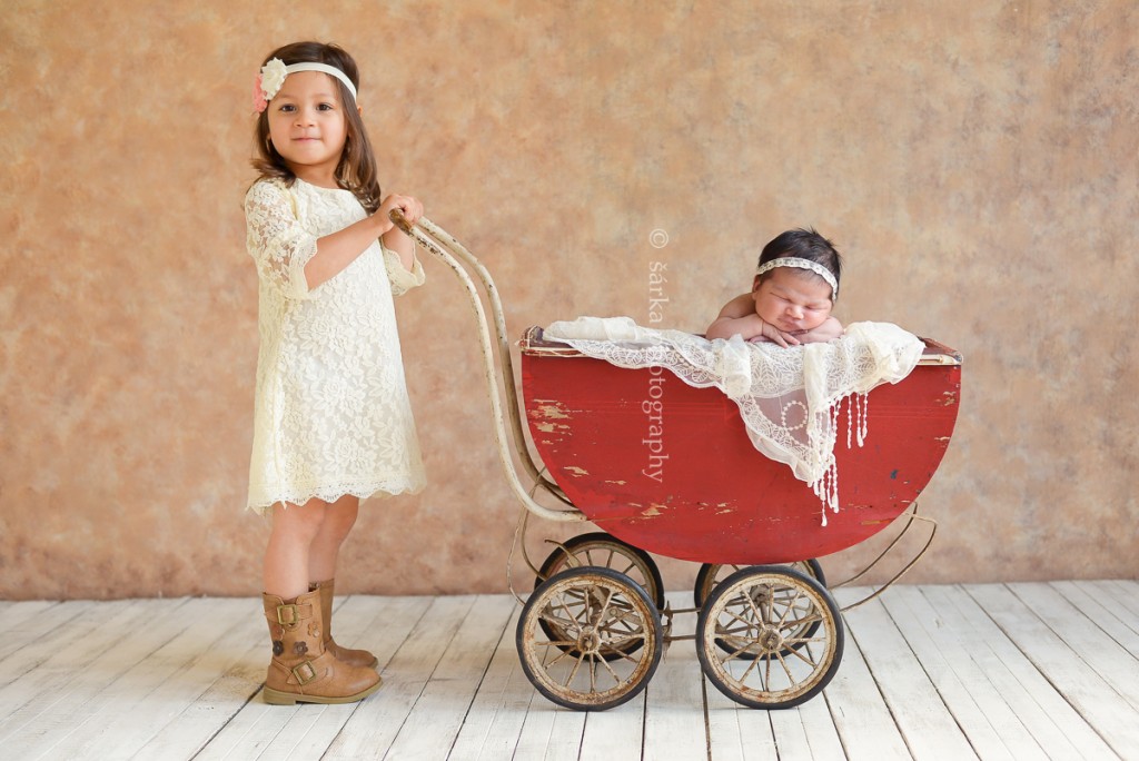 newborn baby girl sleeping in a vintage carriage pushed by her older sister photographed by San Francisco and Marin Bay area newborn photographer Sarka Photography