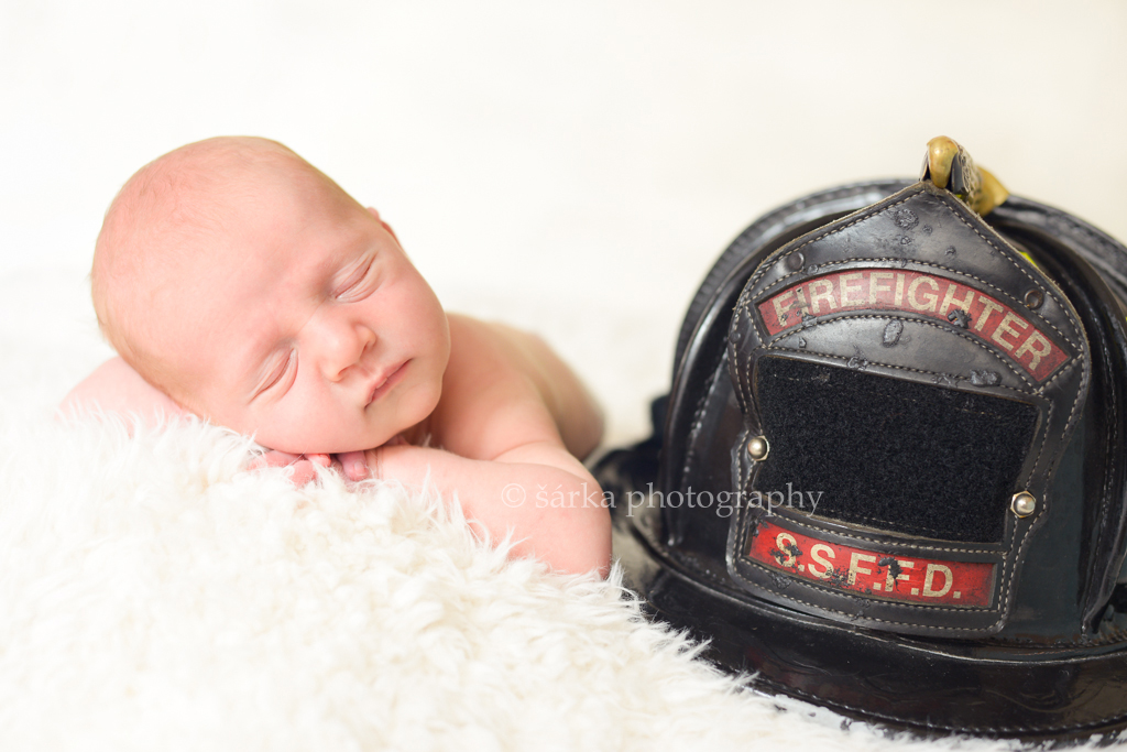 newborn boy sleeping next to his dads firefighter helmet photographed by San Francisco Bay Area newborn and baby photographer Sarka Photography