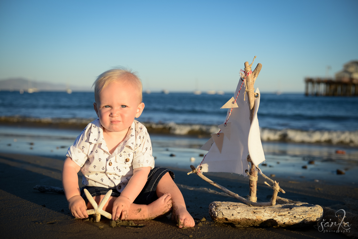 toddler boy playing with handmade driftwood boat on the beach photographed by Santa Barbara baby photographer Sarka Photography