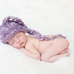 newborn baby girl sleeping in a hand knitted purple hat photographed by San Francisco Bay Area and Santa Barbara baby photographer Sarka Photography