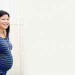 pregnant woman peeking around a corner pregnant woman showing off her belly photographed by Santa Barbara and San Francisco Bay area photographer Sarka Photography