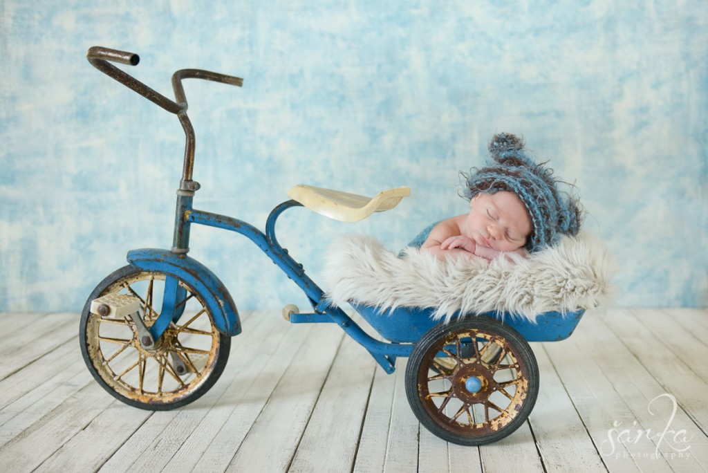 newborn baby boy sleeping in a vintage tricycle photographed by Santa Barbara newborn and baby photographer Sarka Photography