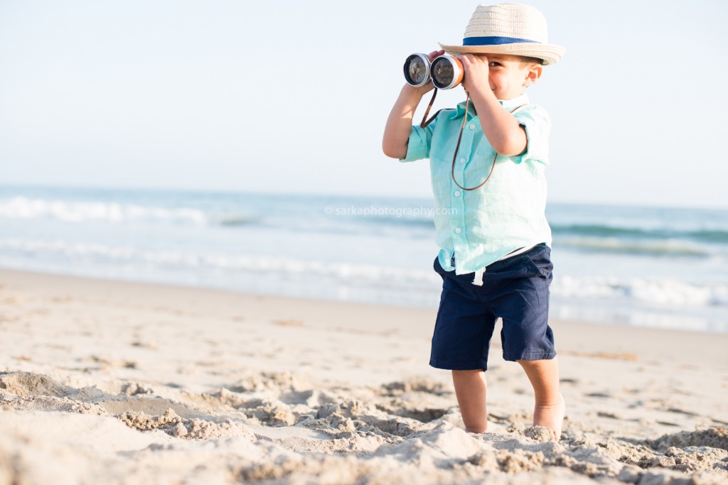 toddler boy looking through vintage binoculars on the beach photographed by Santa Barbara children photographer Sarka Photography
