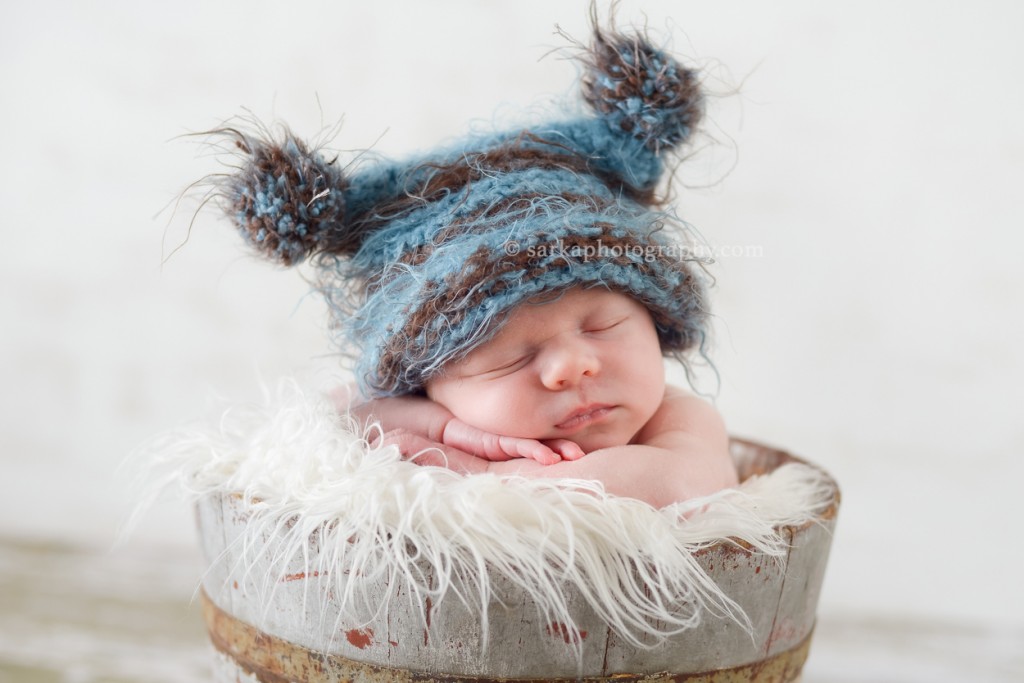 newborn baby boy wearing a hand knitted hat sleeping in a vintage bucket photographed by Marin baby photographer