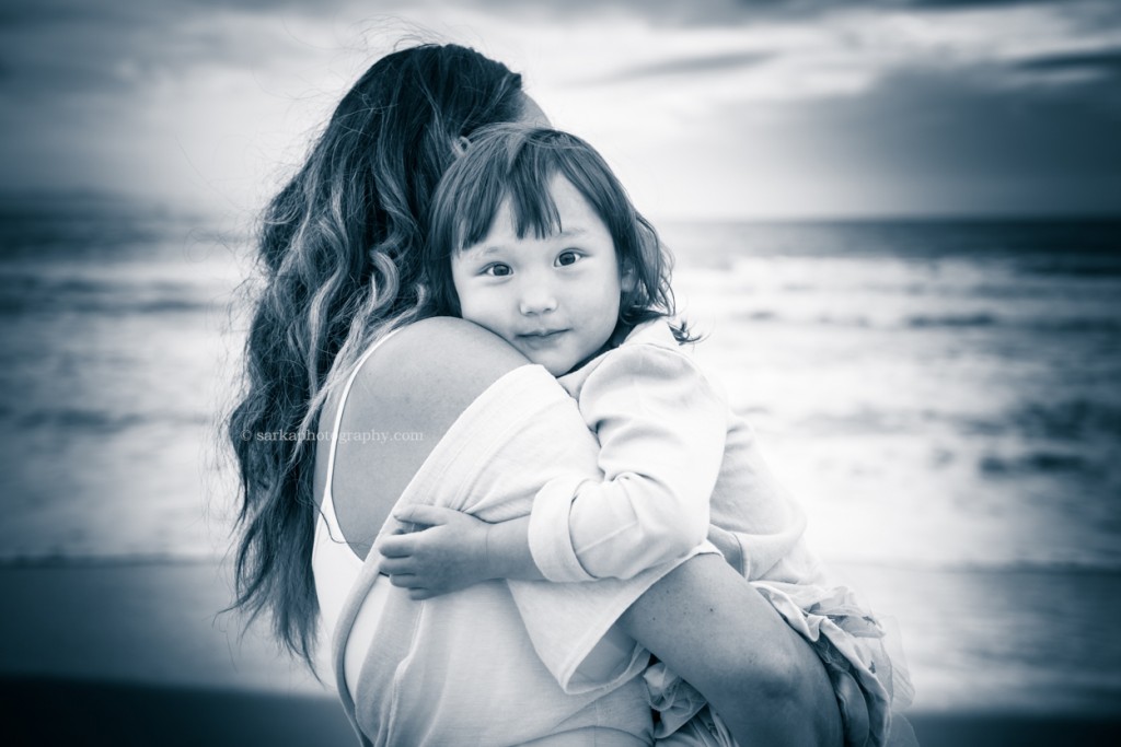 little girl in her moms arms on the beach at sunset photographed by Santa Barbara children and family photographer by Sarka Photography