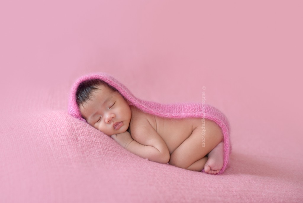 newborn baby girl sleeping on a pink blanket covered with a hand knitted wrap photographed by Santa Barbara and San Francisco Bay area photographer Sarka
