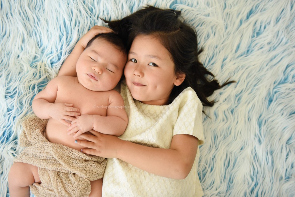 older sister hugging his sleeping baby brother baby boy in a wooden box photographed by Santa Barbara and Burlingame baby photographer Sarka Photography