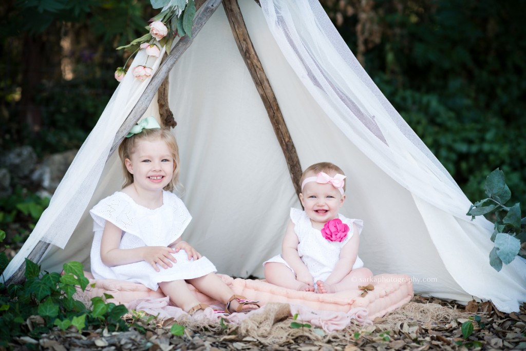 sibling daughters sitting in a flowery tent with Santa Barbara Montecito children portraits photographer sarkaphotography