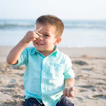 toddler boy playing with a starfish at a family photo session in Carpinteria by sarkaphotography