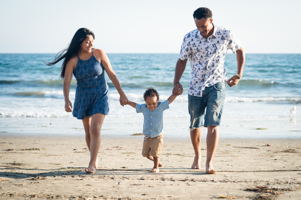 young family walking on the beach during their family photo session in Santa Barbara by Sarkaphotography