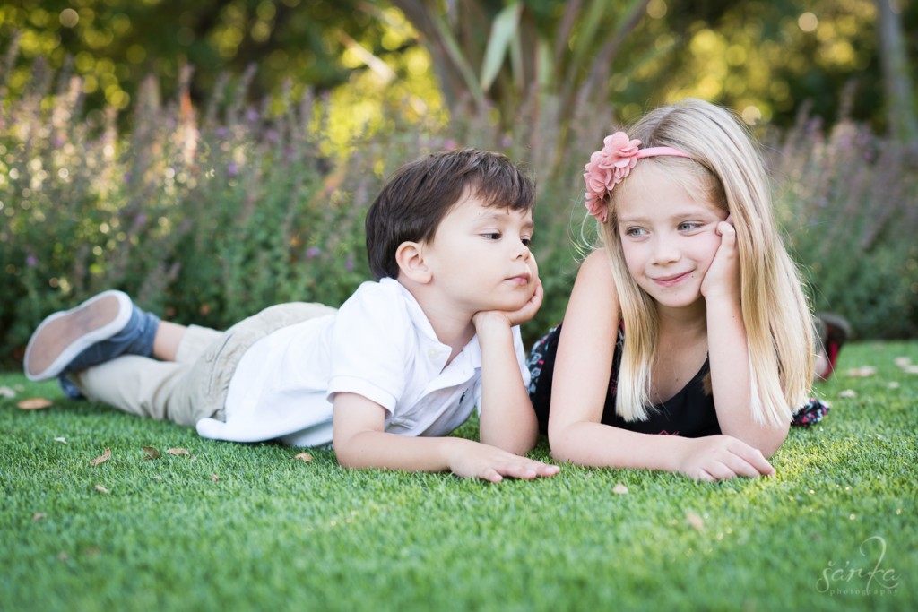 young siblings laying on a grass photographed by bay area burlingame family photographer sarkaphotography