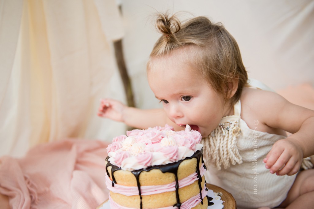 one year girl eating her birthday cake during cake smash photo session by santa barbara baby photographer sarkaphotography