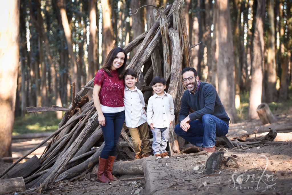 family posing in the woodsy park during their family portraits session by sarkaphotography