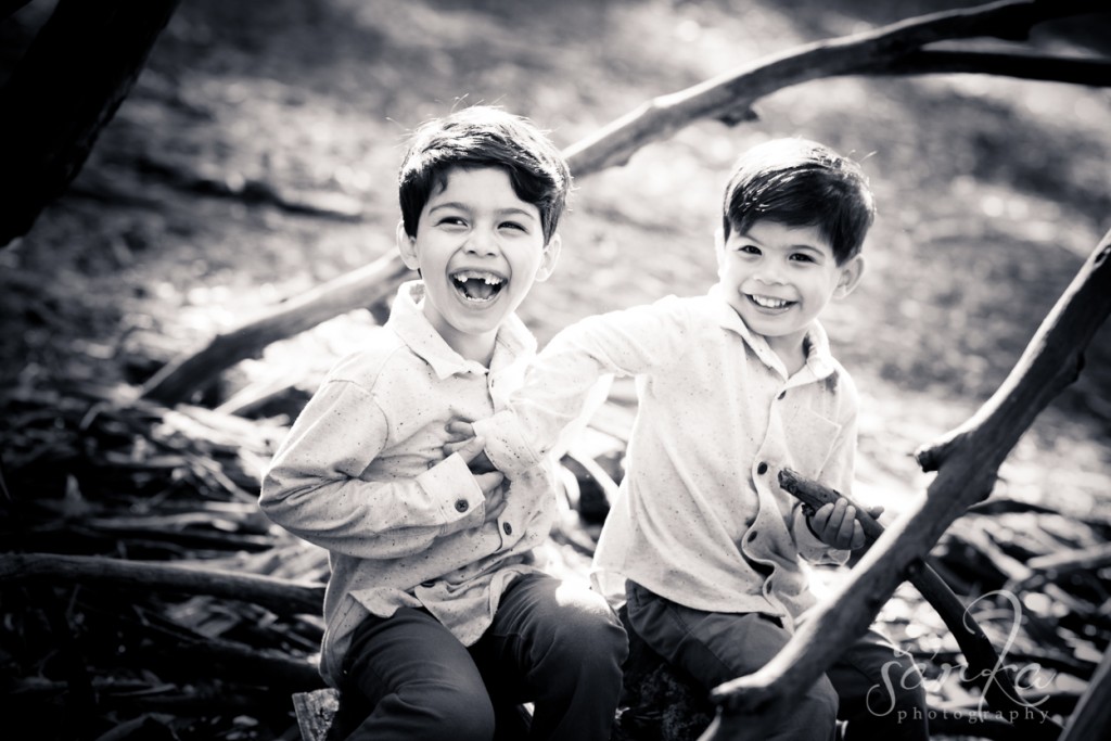 two brothers playing in the woodsy park during their family portraits session by sarkaphotography