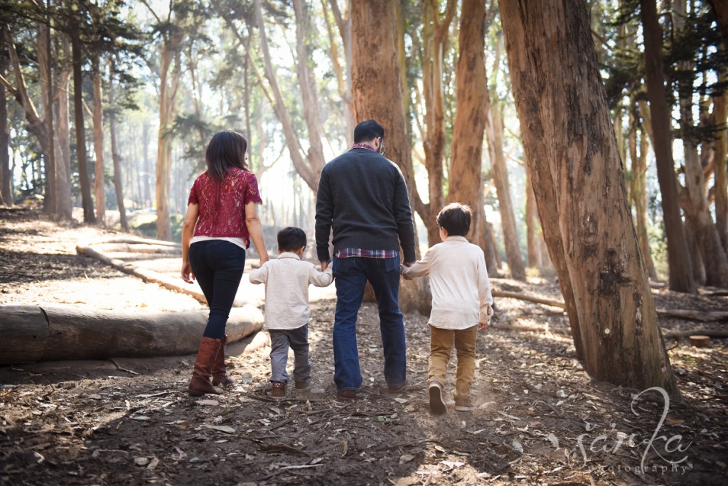 family walking in the woodsy park during their family portraits session by sarkaphotography