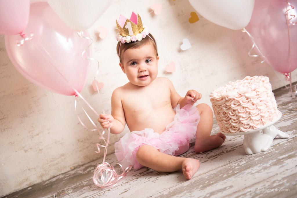 baby girl Aria enjoying her cake during her one year old cake smash photo session by sarkaphotography in Santa Barbara