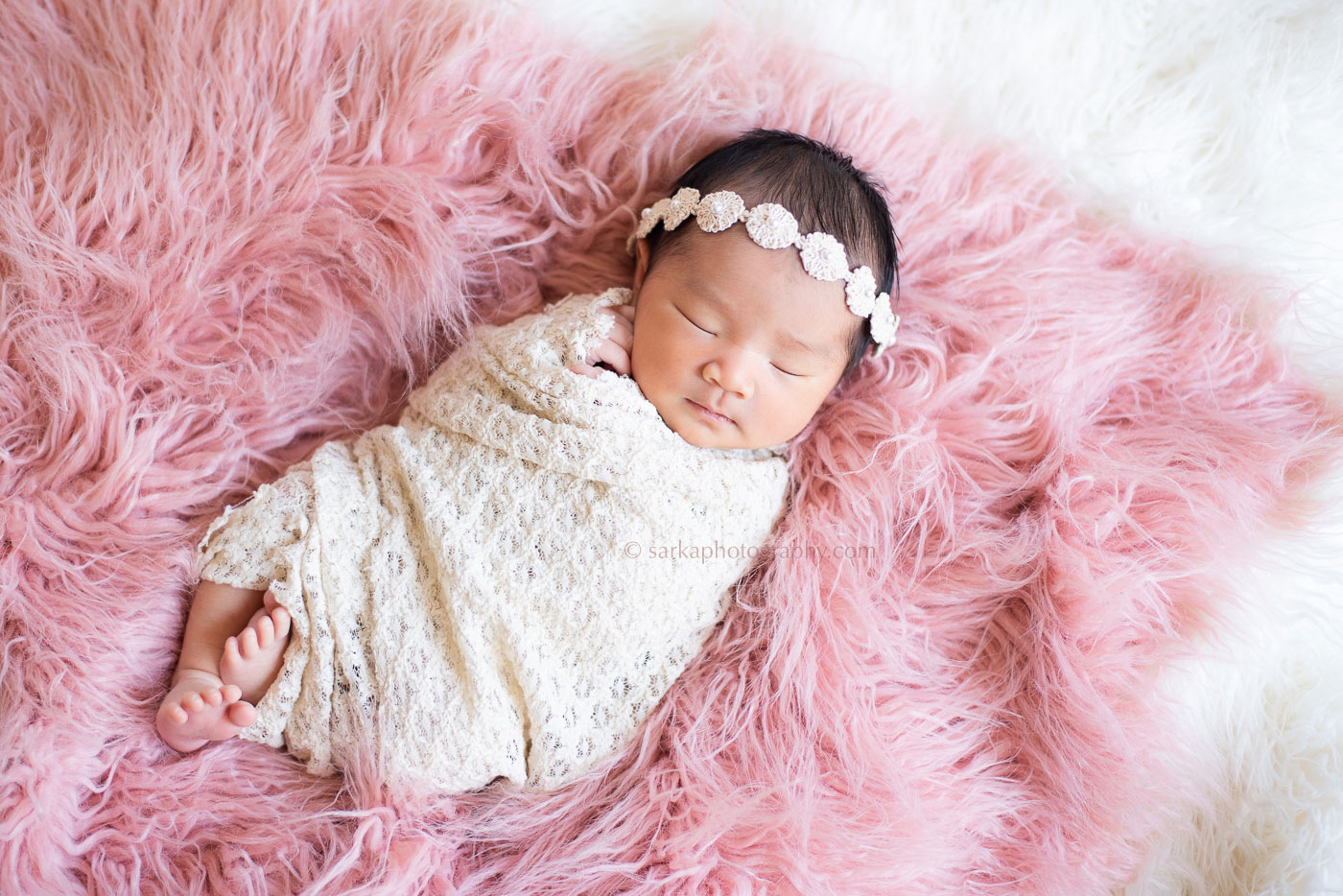 newborn portrait of baby girl sleeping on a pink furry blanket