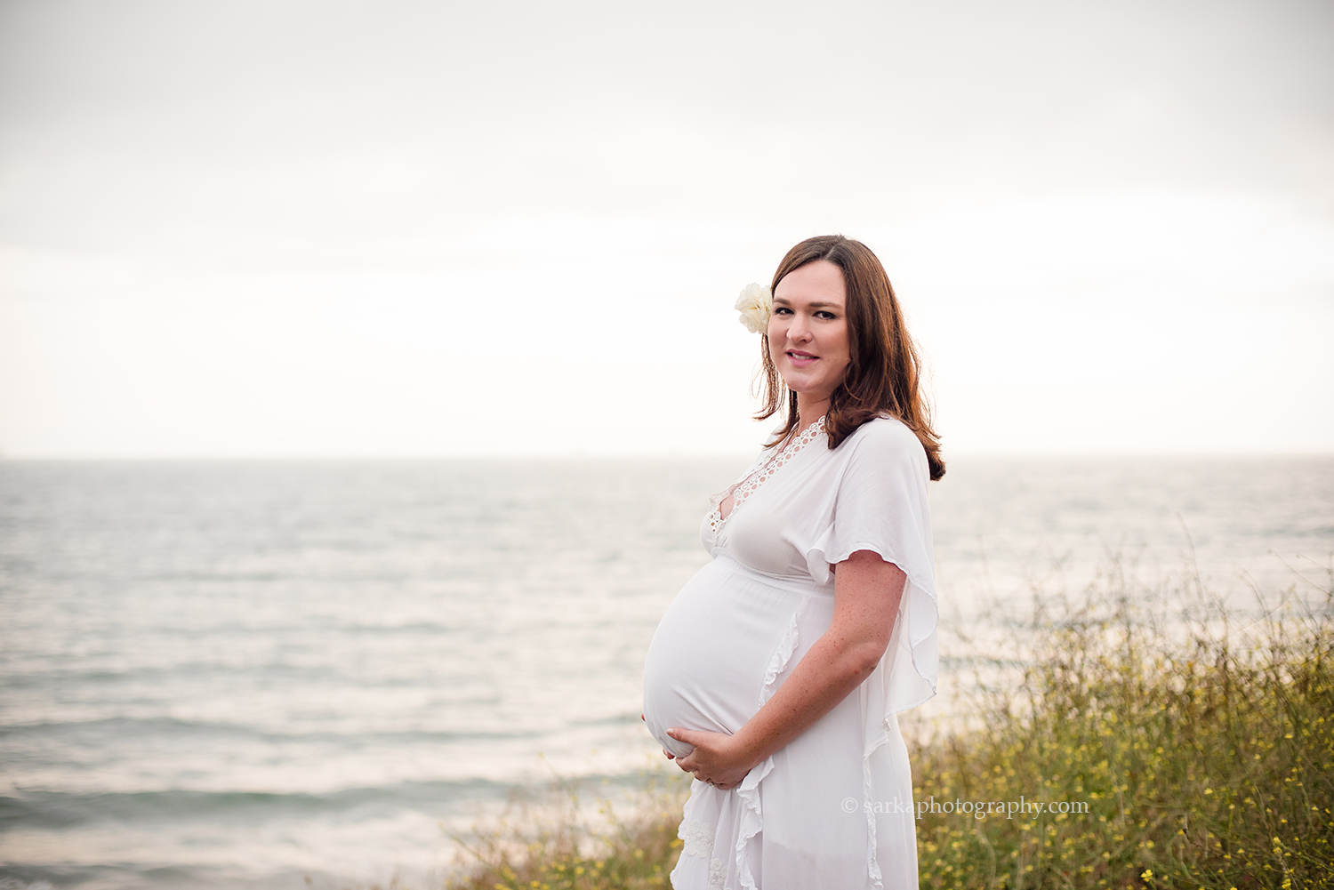 beautiful mom posing with her baby bump on the bluffs overlooking the ocean