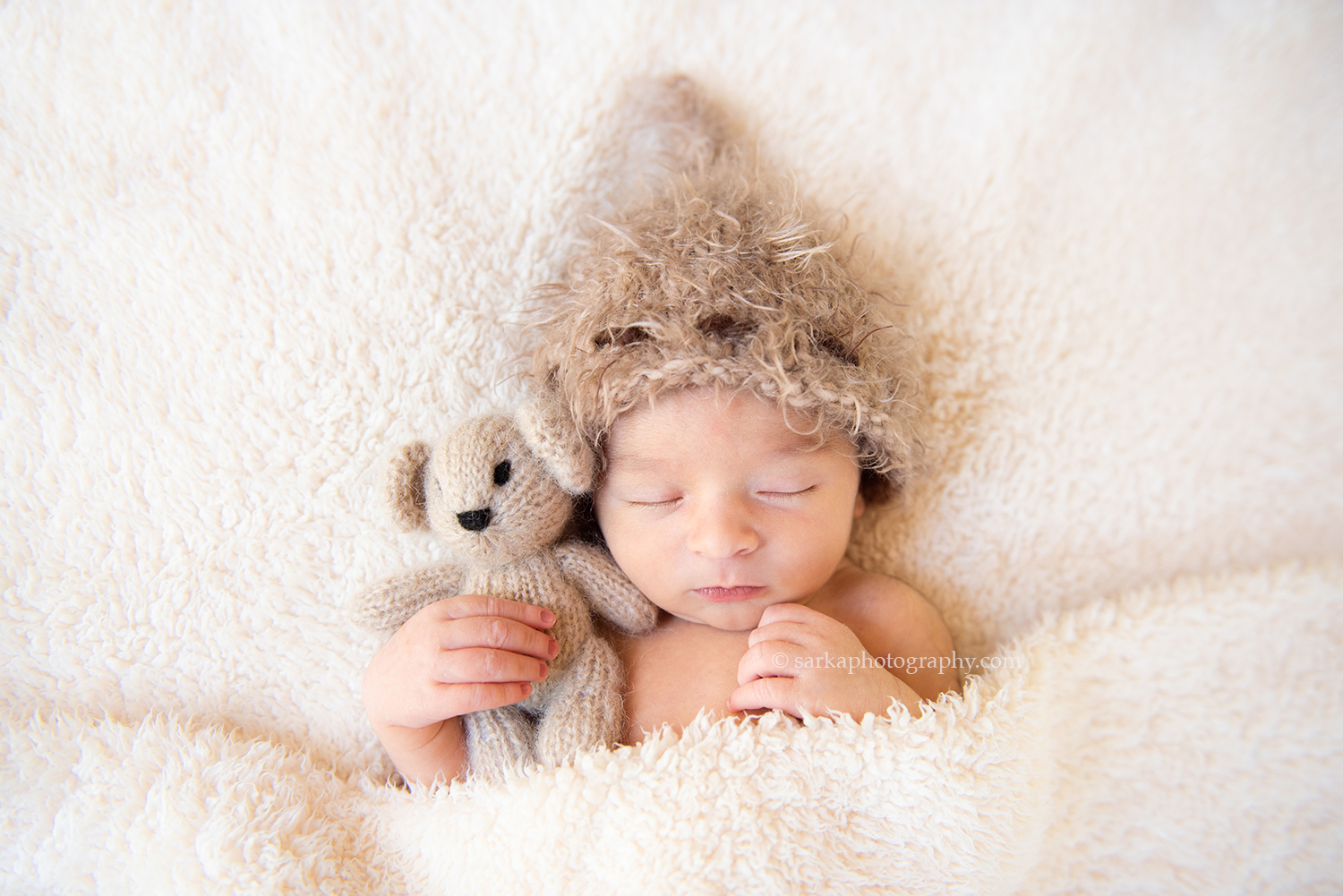 newborn baby boy snuggling with a teddy bear during his newborn photo session in Carpinteria