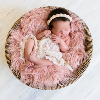 newborn baby girl smiling while sleeping in a vintage basket during her baby photos in Carpinteria