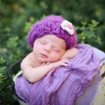 newborn baby girl sleeping in a bucket wearing a purple knitted hat photographed by San Francisco Bay Area and Santa Barbara baby photographer Sarka Photography