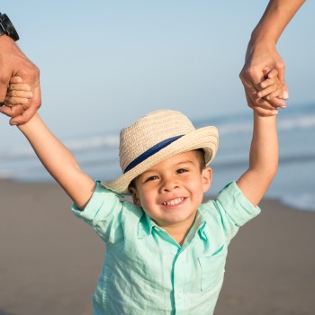 toddler boy holding his parents hands at his family portrait lifestyle photo session in Carpinteria by Santa Barbara children and family photographer sarkaphotography